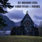 A dark stone chapel with intricate circular windows sits against a backdrop of misty mountains and a cloudy sky, evoking the magical world of Harry Potter.