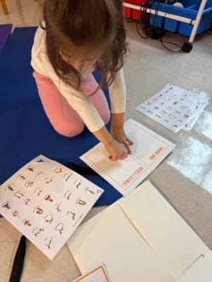 Child placing yoga pose sticker into chakra-colored sticker book