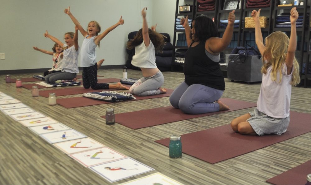 Four children practicing Washing Machine Pose together in a Grounded Kids Yoga class