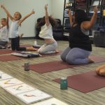 Four children practicing Washing Machine Pose together in a Grounded Kids Yoga class