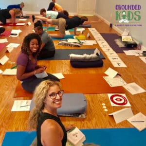 Adults participating in Step 1 kids yoga training with Grounded Kids Yoga, seated on mats with pose cards and materials
