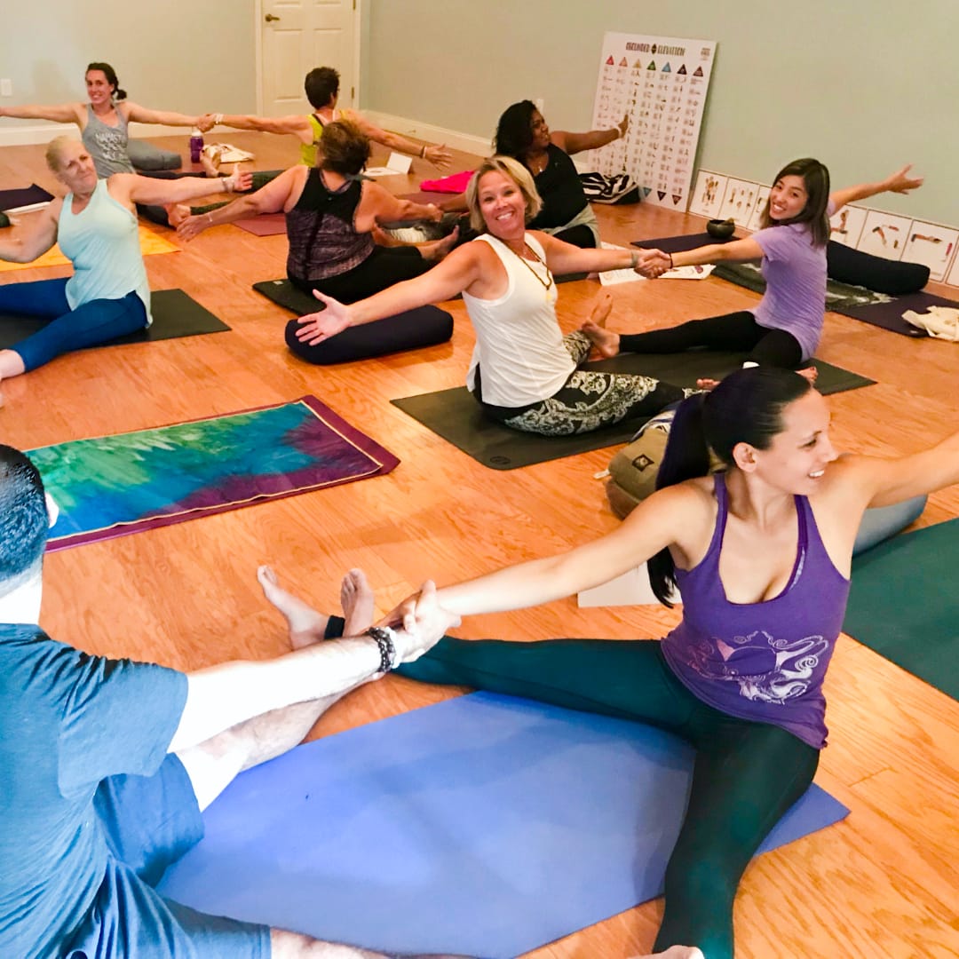 Adults practicing partner yoga in a training circle during Step 4 of the Grounded Kids Yoga certification program