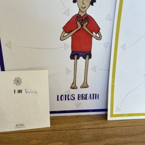 A Lotus Breath pose illustration of a child with hands held together at the chest, beside a card that reads I Am Giving with the word Giving written in by hand.