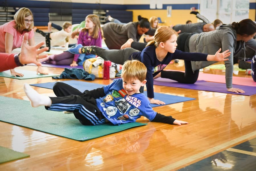Laughing boy on his mat while adults and children balance on hands and knees