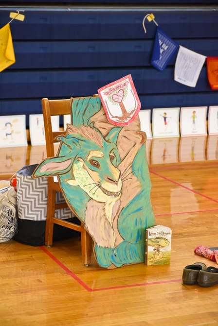 Painted cardboard dragon propped against a chair in a school gym