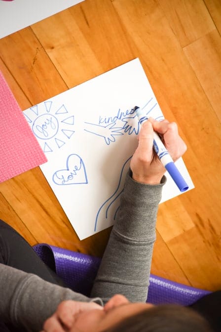 Child drawing a coat of arms with the words Joy, Love and kindness