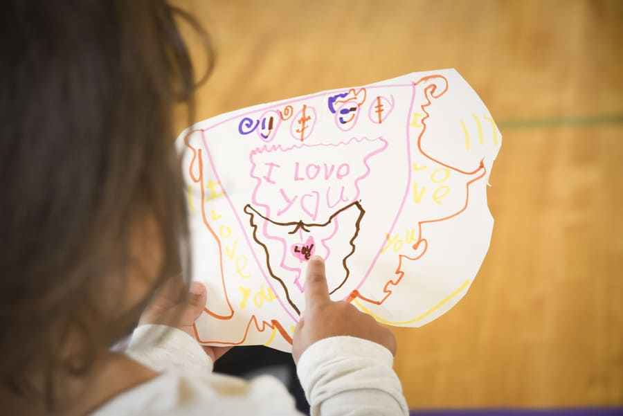 Child pointing to her coat of arms reading I love you