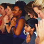 Kids practicing a calming mantra with hands at heart (anjali mudra) in a yoga cla
