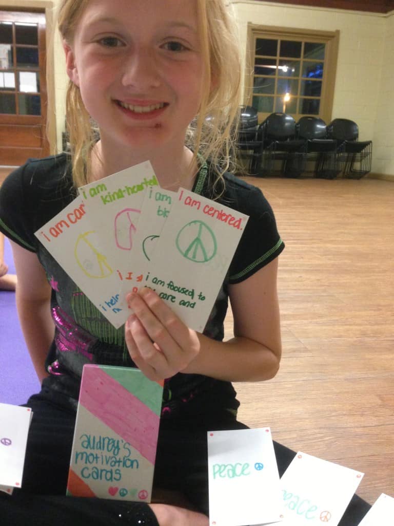 Student presenting a single hand painted “I Am” card after class