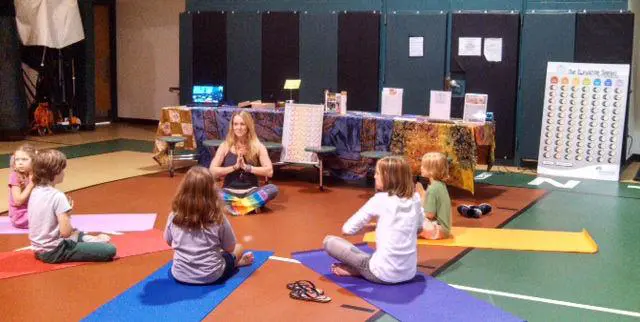 Smiling children practicing yoga poses in a colorful classroom during a Grounded Kids Yoga teacher training session
